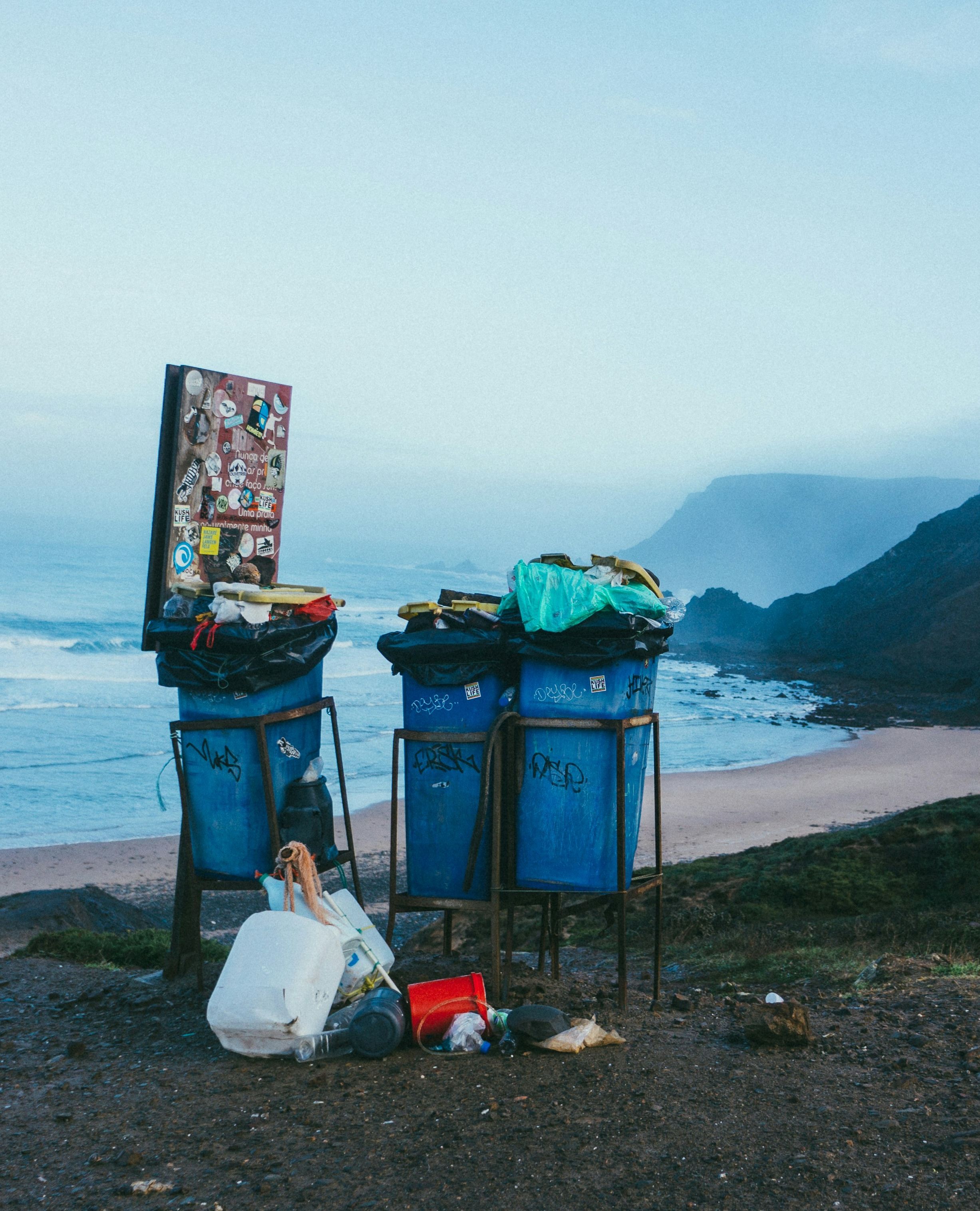 3 blue garbage cans in beach