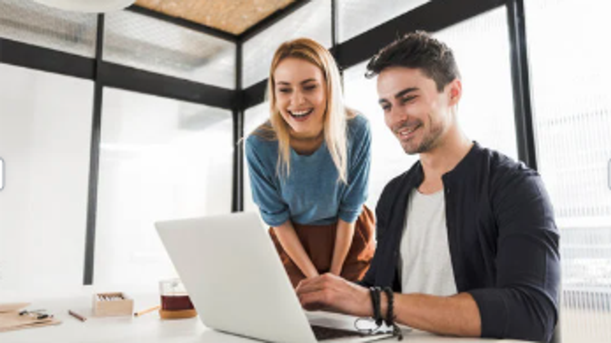 A man and woman look at laptop and smile