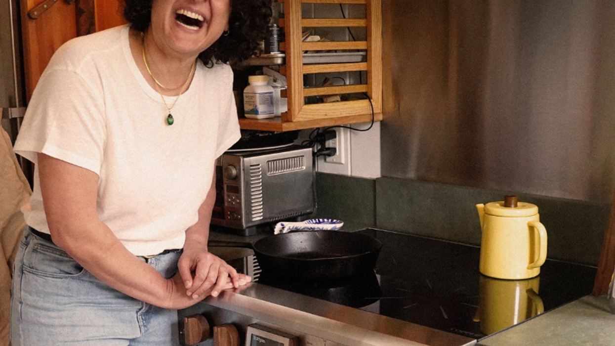 A woman leans over a plug-in, electric stove