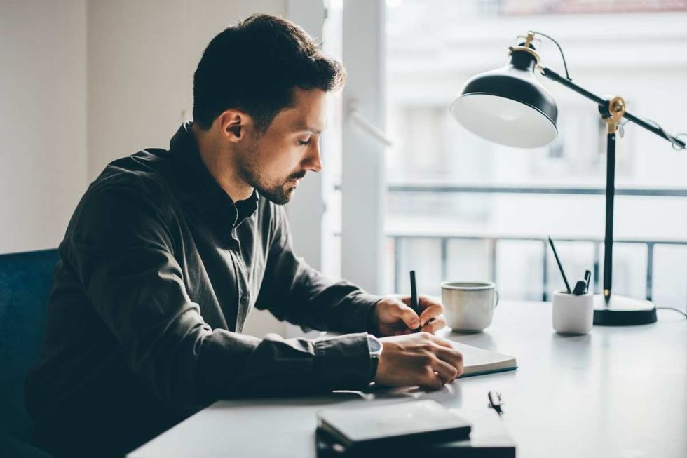Businessman writing in notebook at home (Representative Image Source: Getty Images | Maria Korneeva)