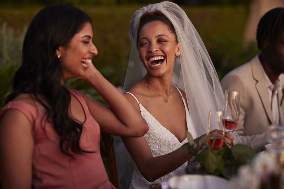 Cheerful bride and bridesmaid at dinner party (Representative Image Source: Getty Images | Klaus Vedfelt)
