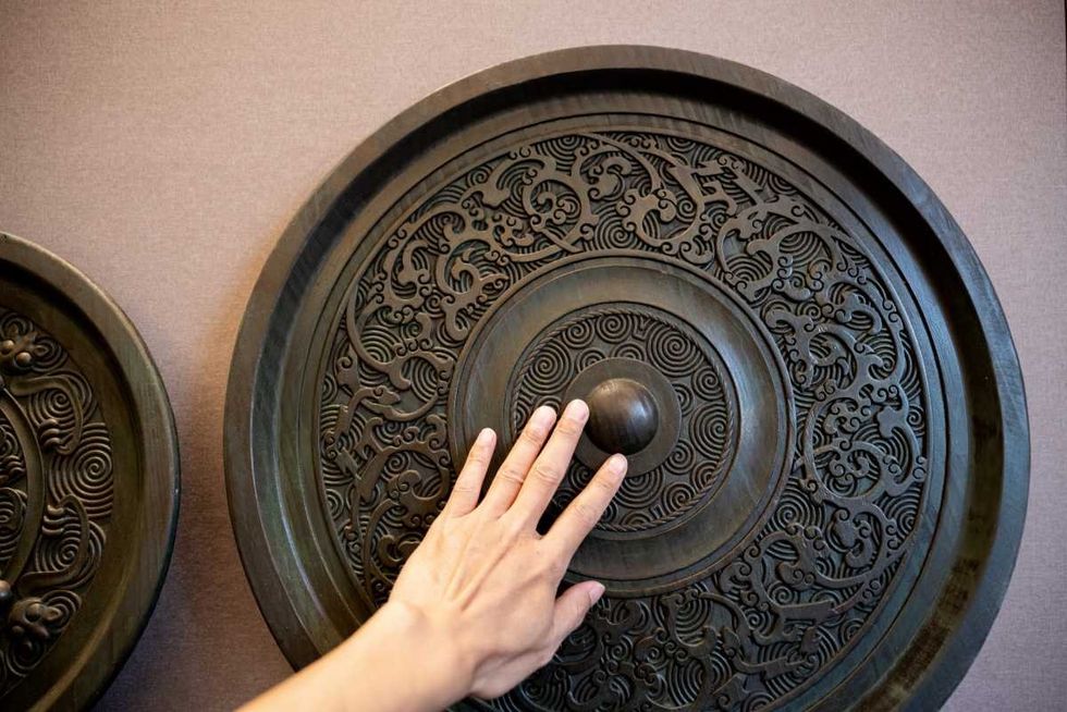 Human hand stroking ancient Chinese bronze mirror (Representative Image Source: Getty Images | Zhihao)