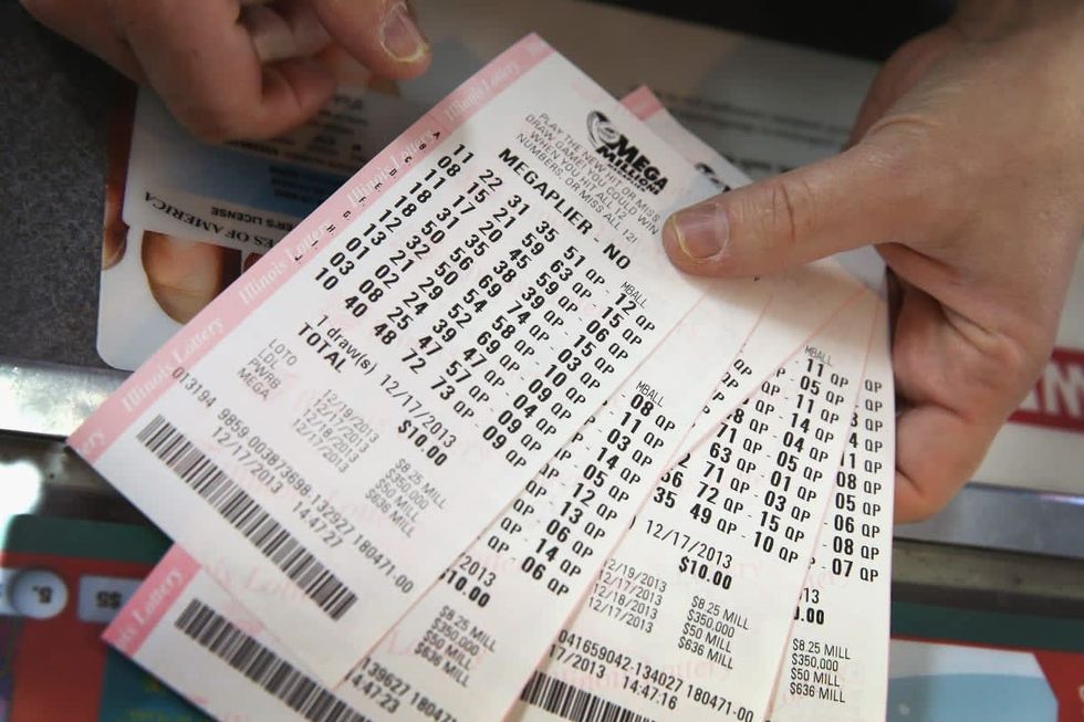 Image Source: A customer holds a stack of Mega Millions lottery tickets which he purchased for his office pool at a convenience store on December 17, 2013 in Chicago, Illinois. (Photo Illustration by Scott Olson/Getty Images)