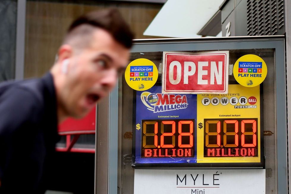 Image Source: : A man rides a bike past advertisements for the Mega Millions and Powerball lottery on July 29, 2022 in New York City. (Photo by John Smith/VIEWpress)