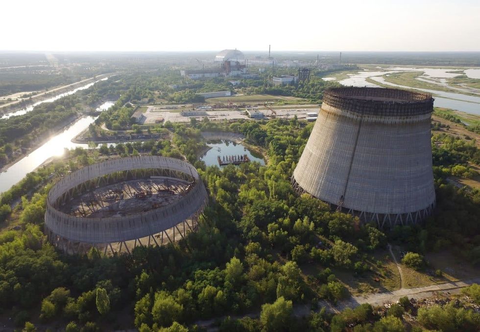 Image Source: In this aerial view abandoned, partially-completed cooling towers stand at the Chernobyl nuclear power plant as the new, giant enclosure that covers devastated reactor number four stands behind on August 18, 2017 near Chornobyl', Ukraine. (Photo by Sean Gallup/Getty Images)