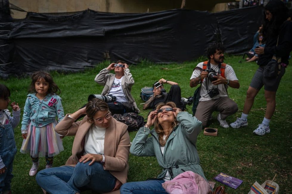 Image Source: People look at annular solar eclipse at Planetarium of Bogota on October 14, 2023 in Bogota, Colombia. (Photo by Diego Cuevas/Getty Images)
