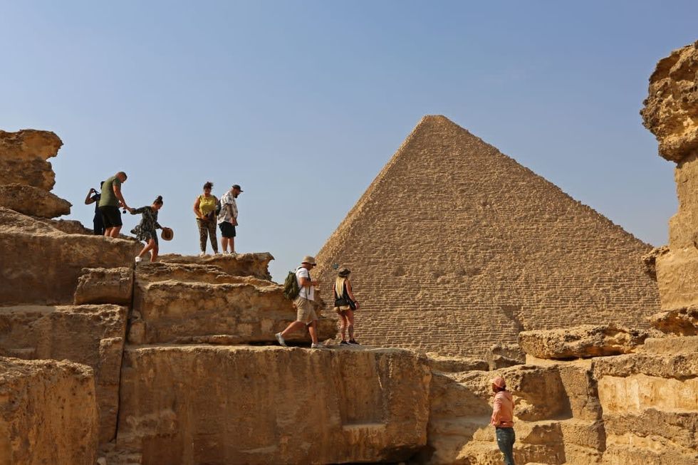 Image Source: Tourists in the pyramids area on June 6, 2022 in Giza, Egypt.The pyramids, named after the Pharaohs of the period, are located in the same area as the tombs of the father, son and grandson, the largest being (King Khufu), the middle pyramid (King Khafre) and the small pyramid (King Mnkaure). (Photo by Fadel Dawod/Getty Images)