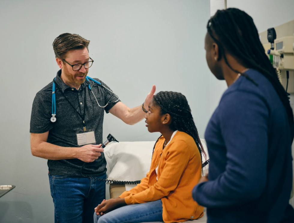 Mom at the doctor's office with her daughter as a physician checks on her.
