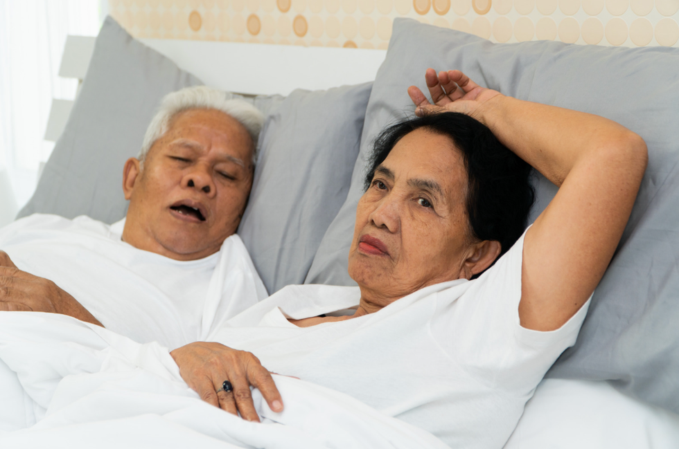 Old couple in bed, man snoring, woman awake