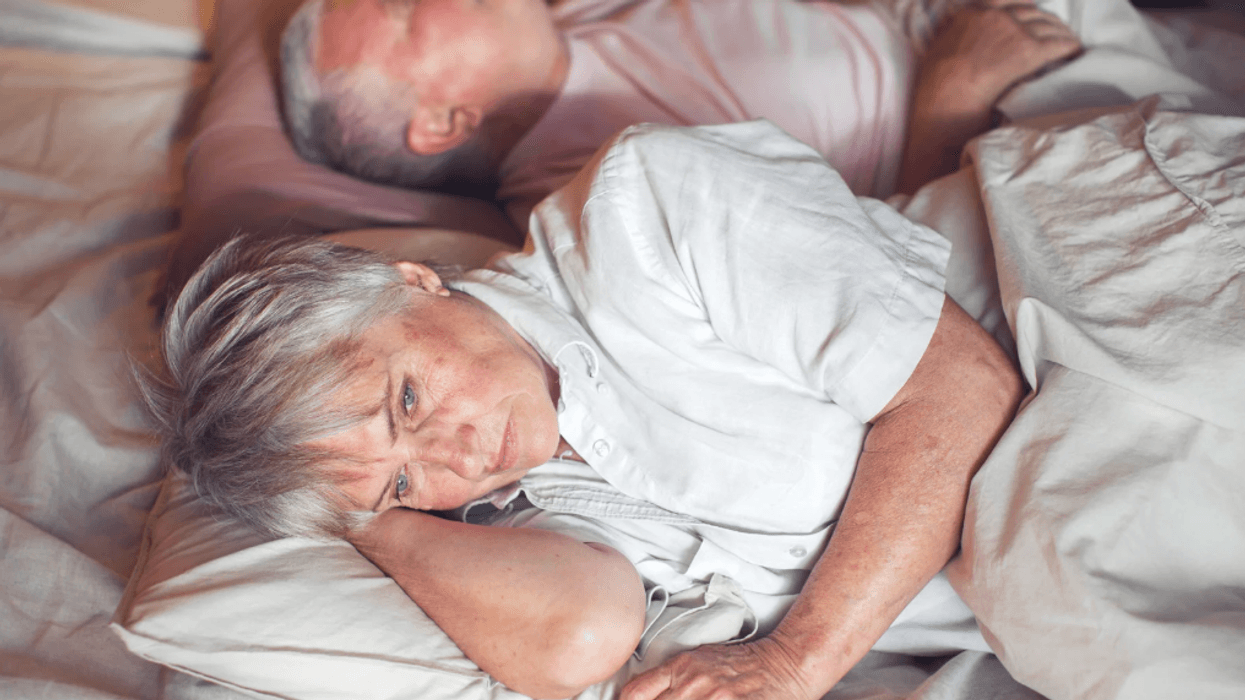 Older couple in bed, woman awake while man asleep