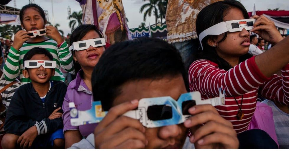 People gather as watch the total solar eclipse in Palembang city on March 9, 2016 in Palembang, South Sumatra province, Indonesia. A total solar eclipse swept across Indonesia on Wednesday, seen by sky gazers and marked by parties, colourful tribal rituals and Muslim prayers. (Photo by Ulet Ifansasti/Getty Images)
