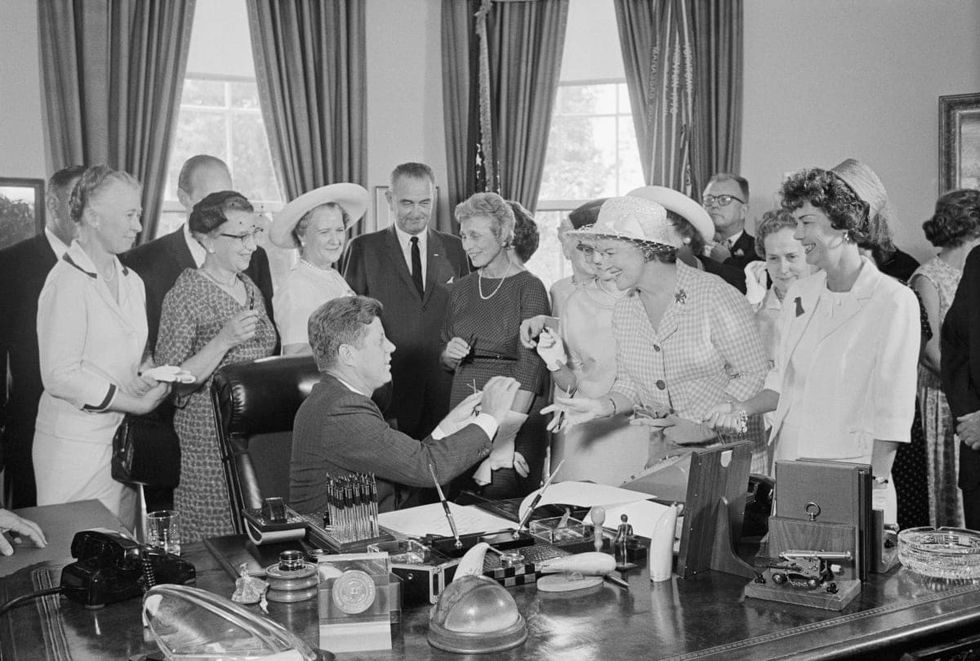 President Kennedy hands out pens during a ceremony at the White House today in which he signed into law a bill aimed at assuring women of paychecks equal to those of men doing the same work.