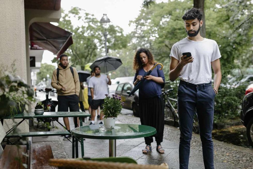Representative Image Source: A group of people following social distancing guidelines waiting in the street to enter a busy restaurant. (Getty Images)
