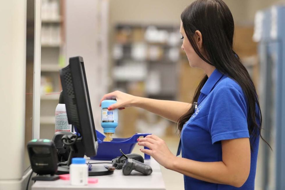 Representative Image Source: A pharmacy technician fills a container with pills to put into a drug dispensing machine for an automated line at the central pharmacy. (Photo by George Frey/Getty Images)