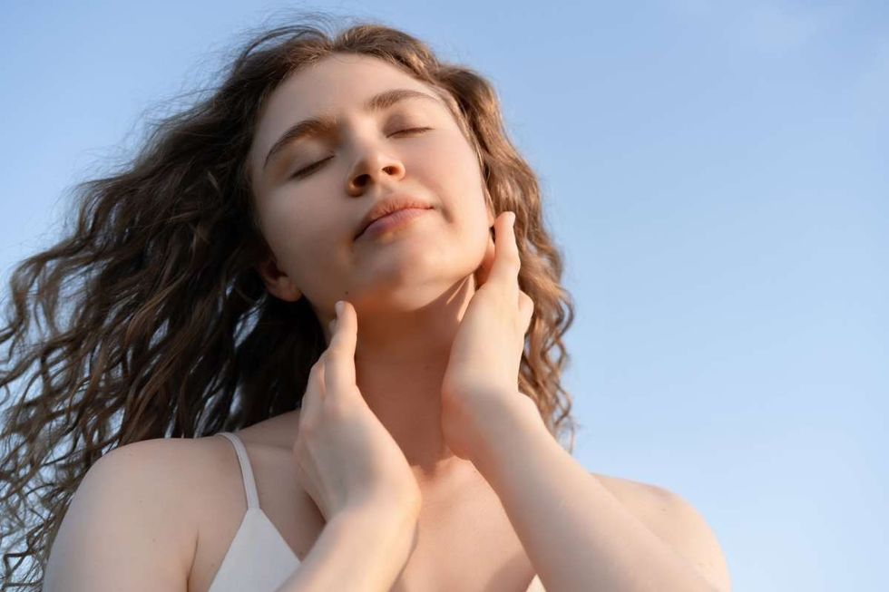 Representative Image Source: Beautiful curly haired woman enjoying sunset outdoors. She is touching her neck and jawline, eyes closed. (Getty Images)