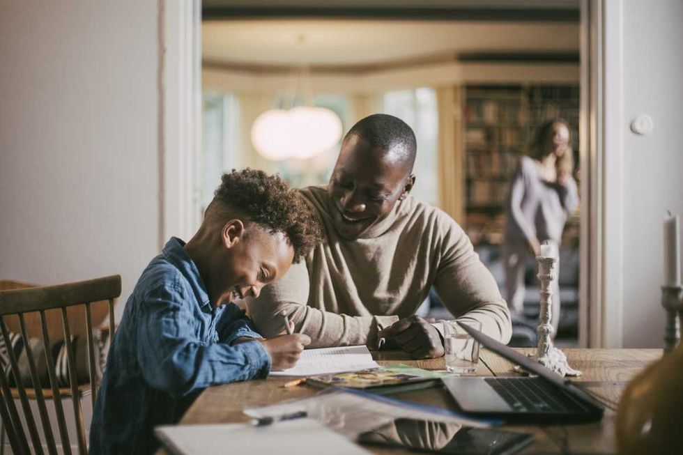 Representative Image Source: Side view of smiling son writing while studying by father over table at home (Getty Images)