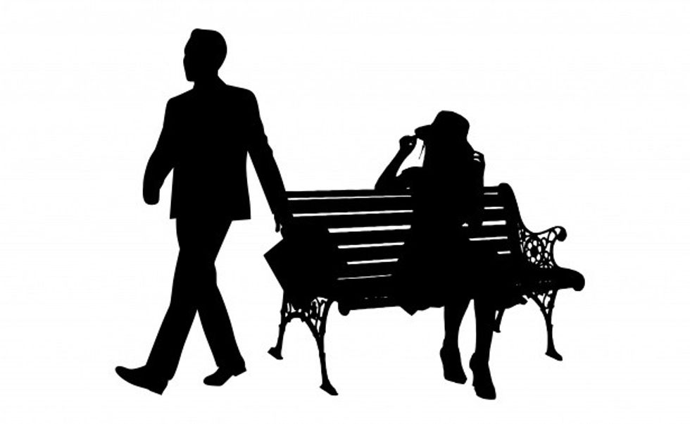 silhouette image of a woman sitting on a bench and a man walking away from her
