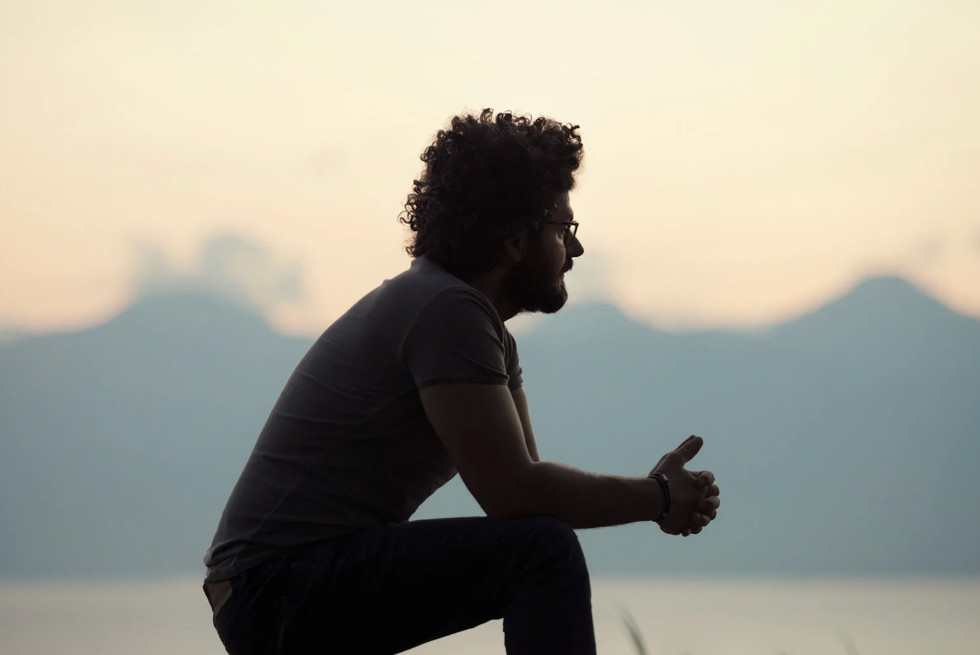 Silhouette of a man sitting alone outside