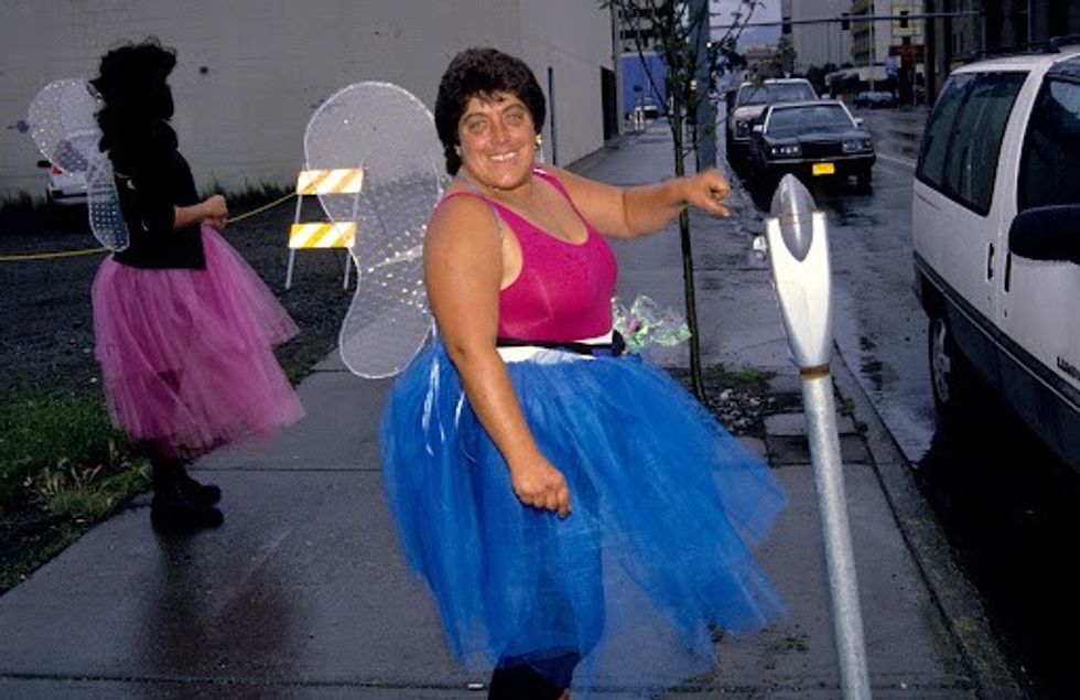 Two women dressed like fairies next to parking meters.