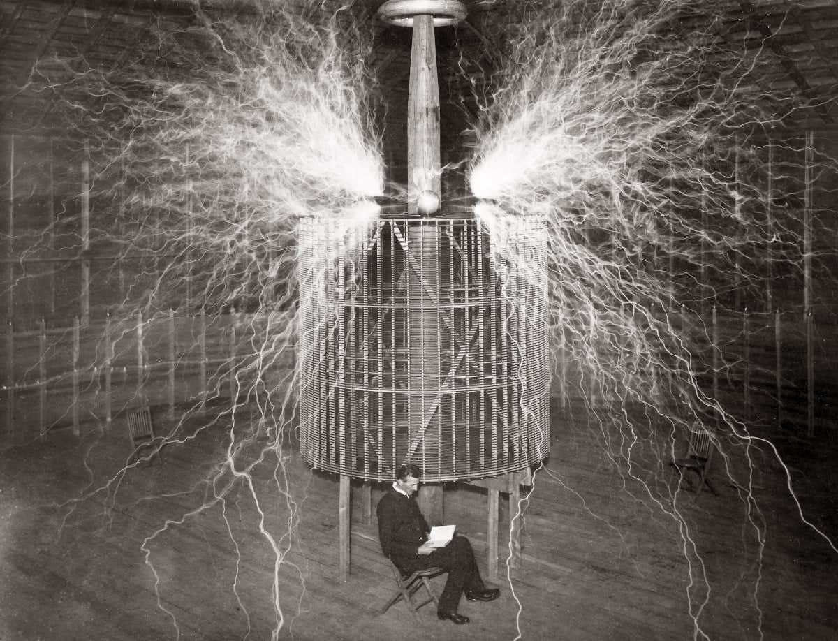 Image Source: Nikola Tesla (1856-1943), Serbian-American physicist sitting in his Colorado Springs laboratory with his