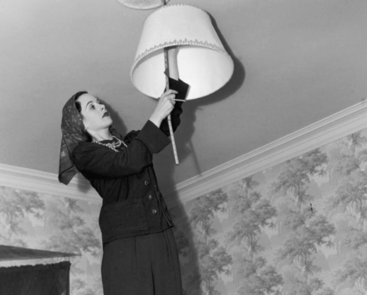 Image source: Austrian-born actor Hedy Lamarr (1913 - 2000) standing on her dining room table and measuring a lampshade. Lamarr, who is wearing a kerchief around her head, was preparing for redecorating. (Photo by Gene Lester/Getty Images)
