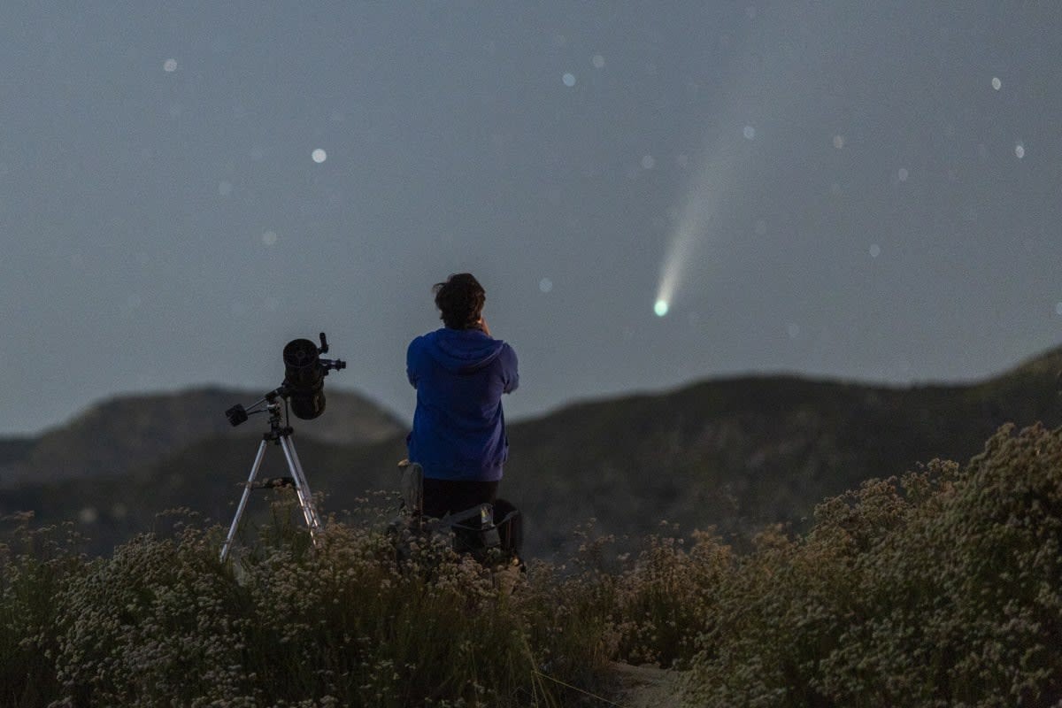 Image Source: A man with a telescope watches the night sky as Comet NEOWISE appears over the San Gabriel Mountains National Monument on July 19, 2020 northwest of Los Angeles, California. (Photo by David McNew/Getty Images)