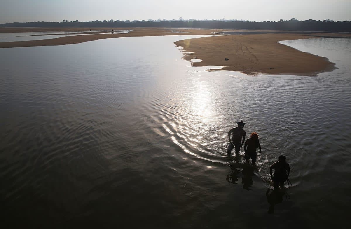 Members of the Munduruku indigenous tribe walk on the banks of the Tapajos River as they prepare a protest against plans to construct a hydroelectric dam on the river in the Amazon rainforest on November 26, 2014 near Sao Luiz do Tapajos, Para State, Brazil
