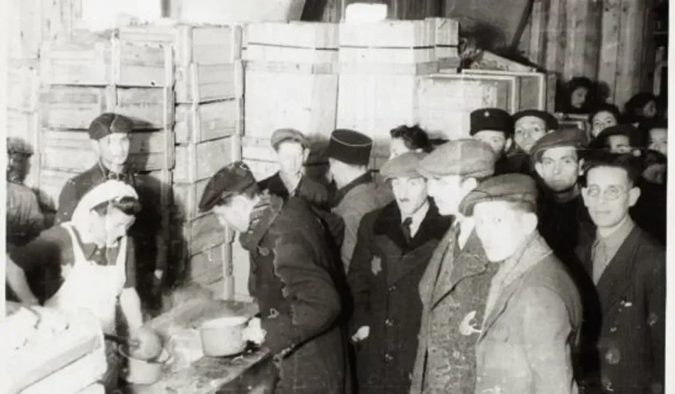 Cook ladling soup into pails for captives.