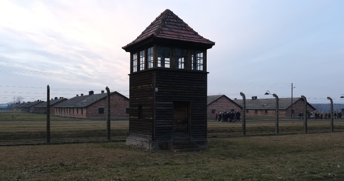 Image Source: A guard tower stands at the perimeter next to barbed wire and former prisoner barracks as visitors huddle at the former Auschwitz-Birkenau German concentration camp on January 26, 2020 near Oswiecim, Poland. (Photo by Sean Gallup/Getty Images)