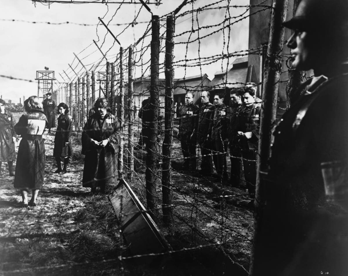 Image Source: An electrified barbed-wire fence separates male and female prisoners at a German concentration camp. A Nazi guard keeps watch in the foreground. Location: Germany. (Photo by © Hulton-Deutsch Collection/Corbis via Getty Images)