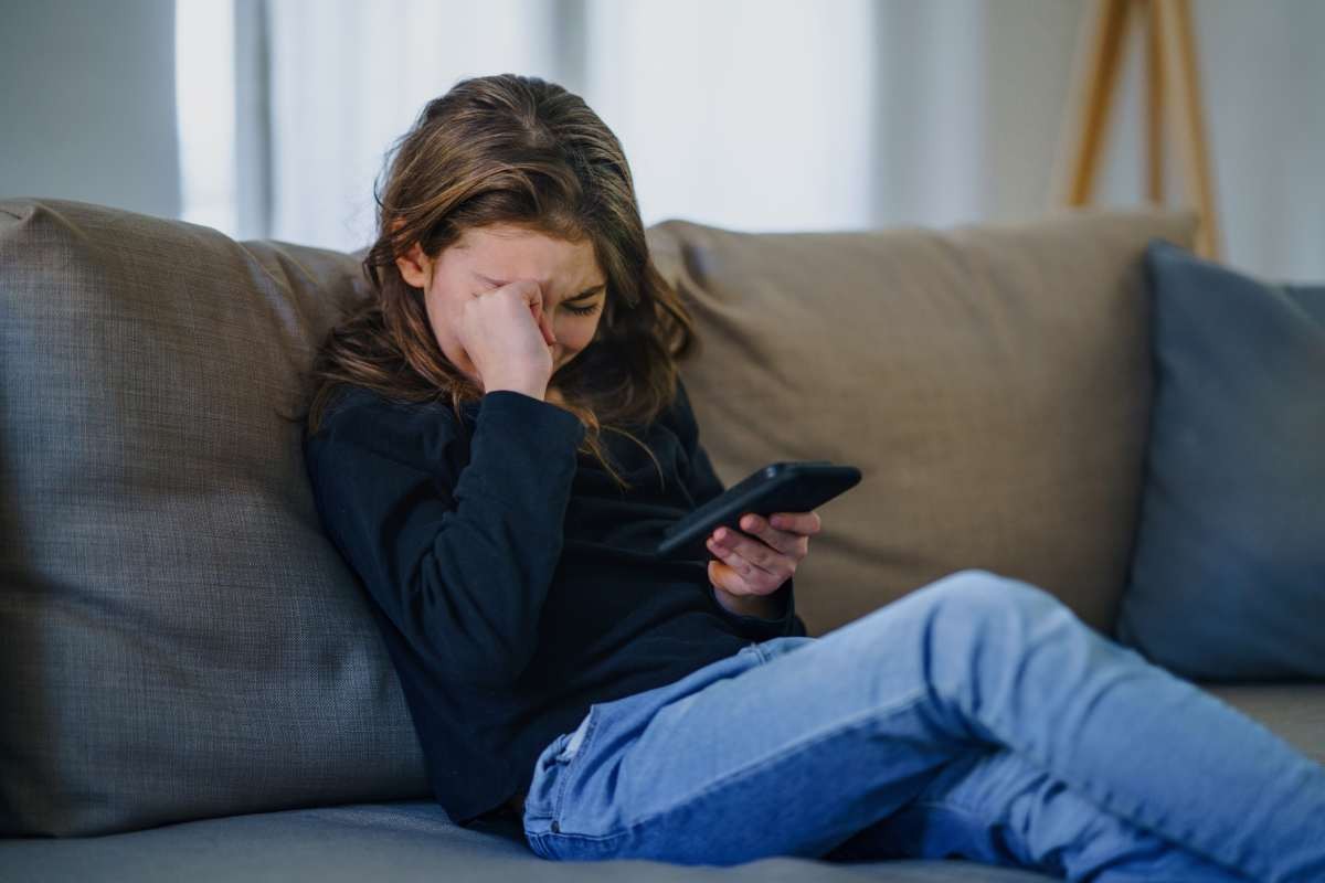 Representative Image Source: Small girl with smartphone sitting indoors on sofa, crying (Getty Images)