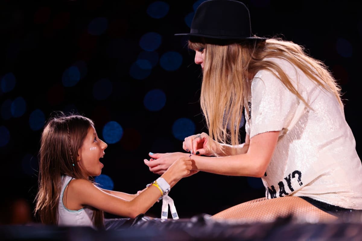 SAO PAULO, BRAZIL - NOVEMBER 24: (EDITORIAL USE ONLY. NO COVERS.) A young fan exchanges friendship bracelets with Taylor Swift as she performs onstage during
