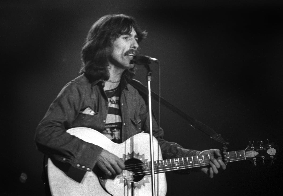 Image Source: English Pop and Rock musician George Harrison plays guitar as he performs onstage at Olympia Stadium, Detroit, Michigan, December 4, 1974. (Photo by Steve Kagan/Getty Images)
