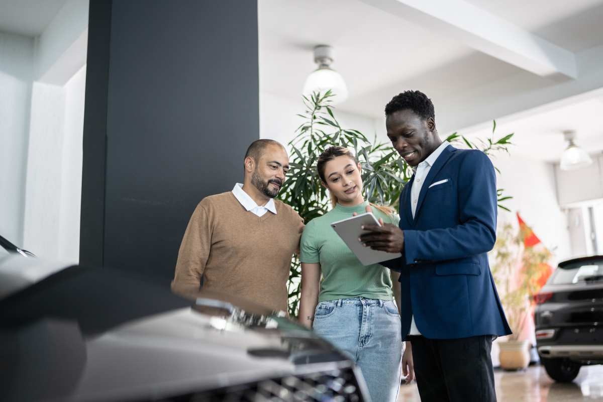 Representative Image Source: Car salesman using a digital tablet talking about a new car to customers in a store. (FG Trade/ Getty Images)