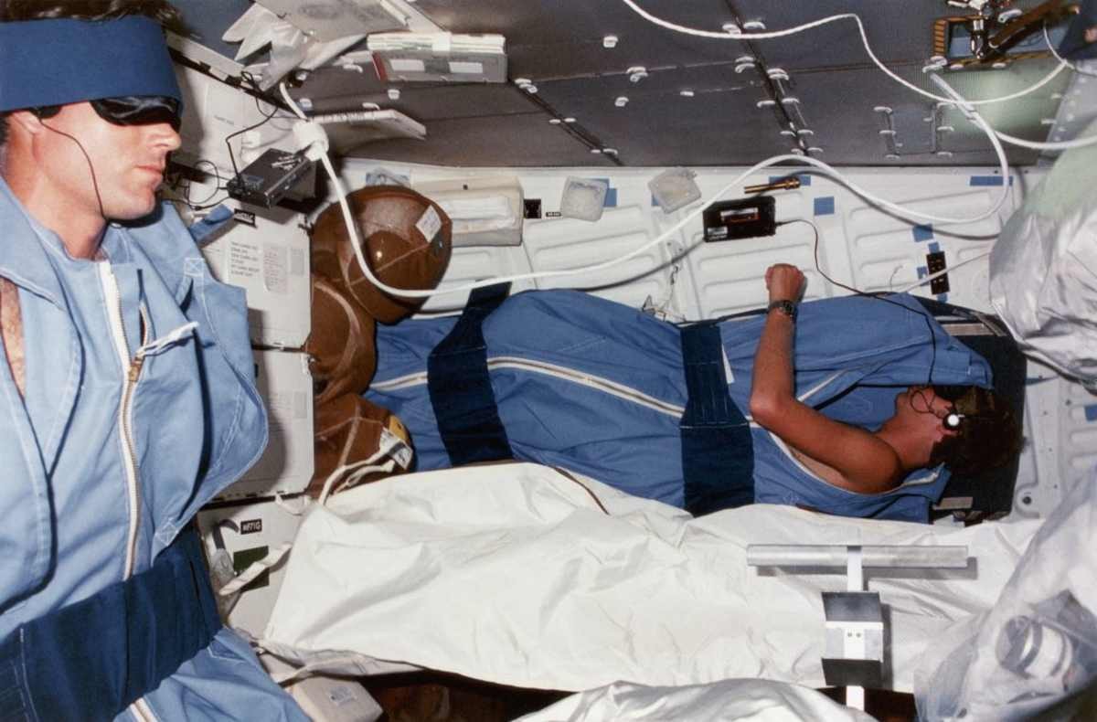 Image Source: STS-41-D crew members Michael L. Coats (pilot, left) and Steven A. Hawley (mission specialist, right) fall asleep listening to music on the lower deck of the shuttle Discovery, 1984. (Photo by Space Frontiers/Getty Images)