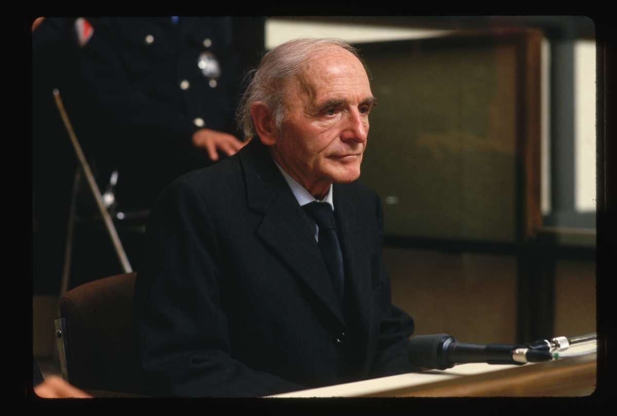 Image Source: Former Gestapo officer Klaus Barbie sits behind a glass screen before the Lyon Assize court at the opening of his trial. (Photo by Peter Turnley/Corbis/VCG via Getty Images)