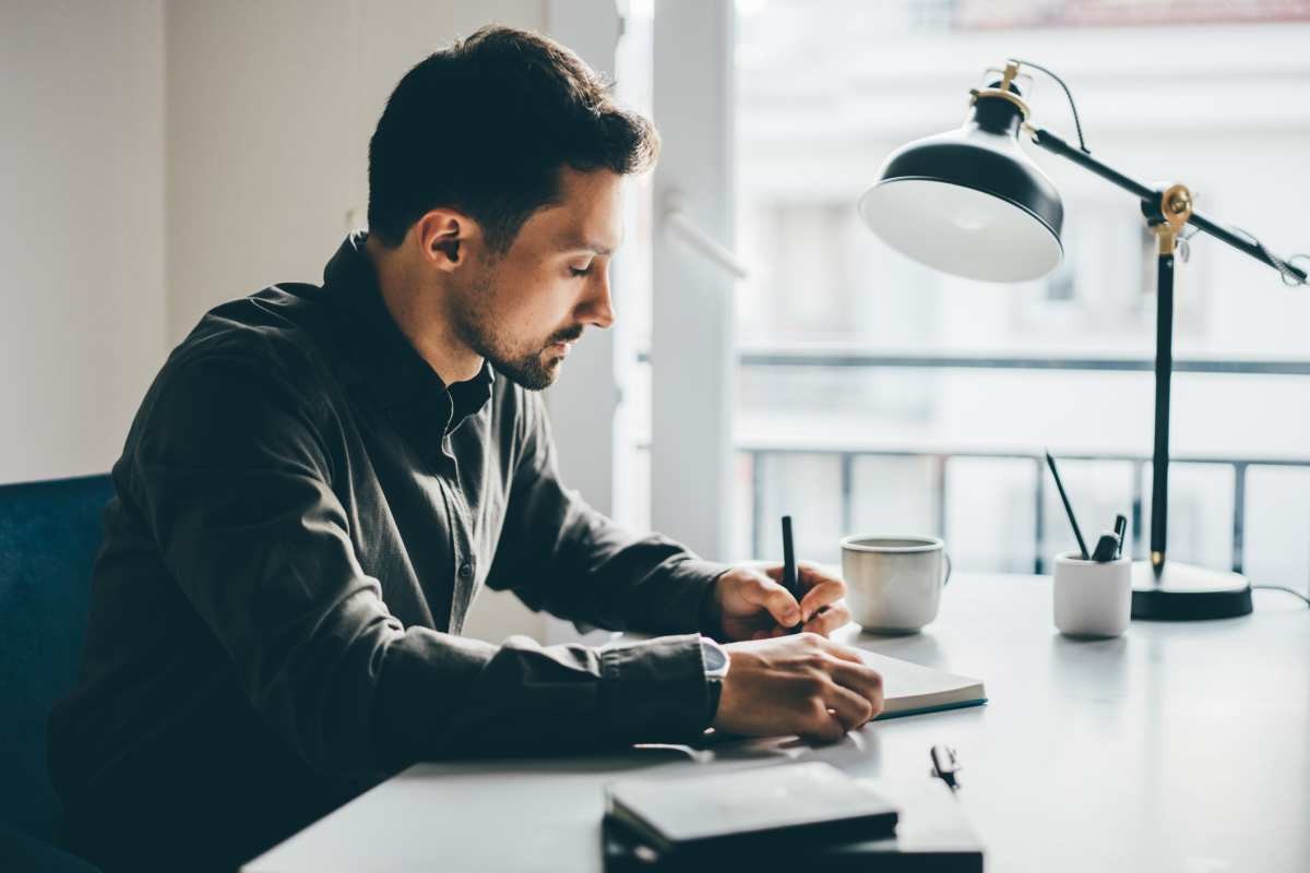 Businessman writing in notebook at home (Representative Image Source: Getty Images | Maria Korneeva)