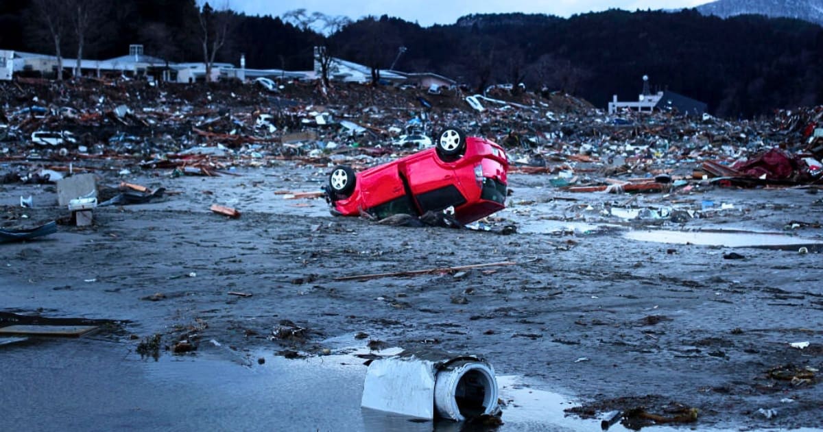 Image Source : Destroyed vehicles lie near the rubble after the earthquake and tsunami devastated the area on March 16, 2011 in Minamisanriku, Japan. The 9.0 magnitude strong earthquake struck offshore on March 11 at 2:46pm local time, triggering a tsunami wave of up to ten metres which engulfed large parts of north-eastern Japan. The death toll continues to rise and could well reach 10,000 in a tragedy not seen since World War II in Japan. (Photo by Chris McGrath/Getty Images)