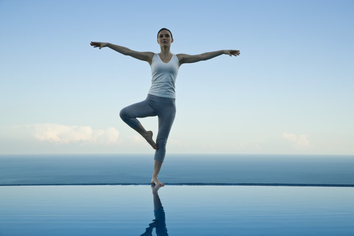 Woman standing in tree pose on edge of infinity pool (Representative Image Source: Getty Images | PhotoAlto/Sigrid Olsson)