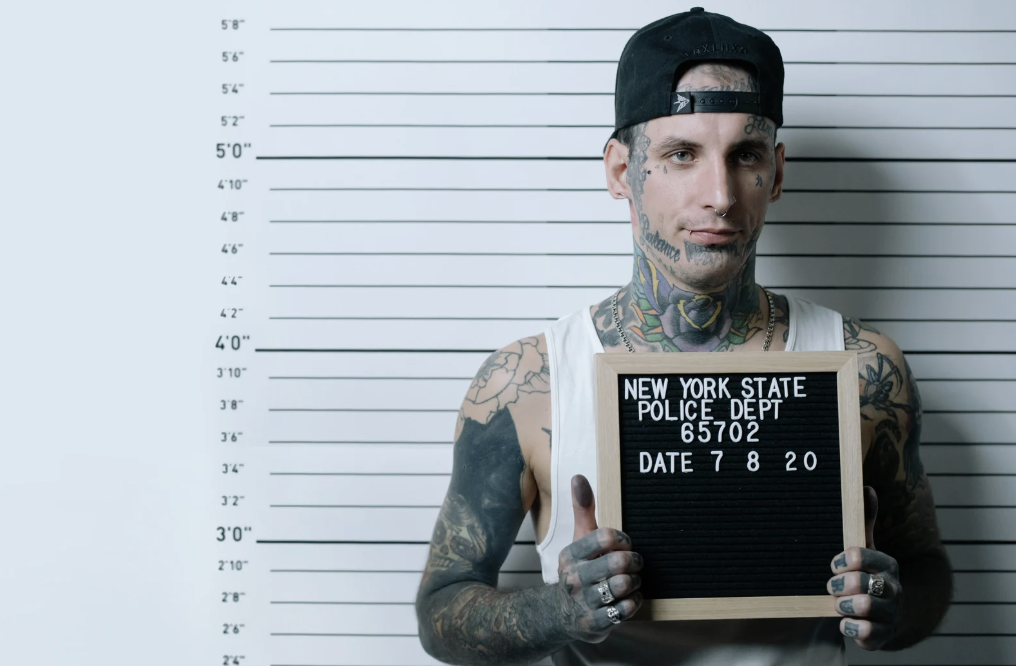 Tattooed man getting mugshot taken