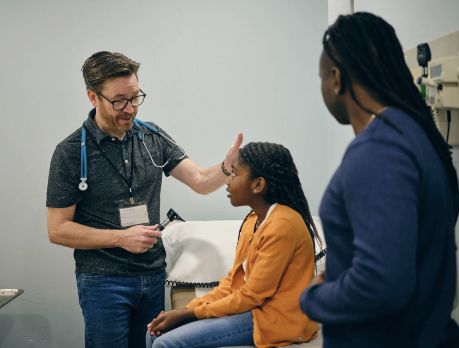 Mom at the doctor's office with her daughter as a physician checks on her.