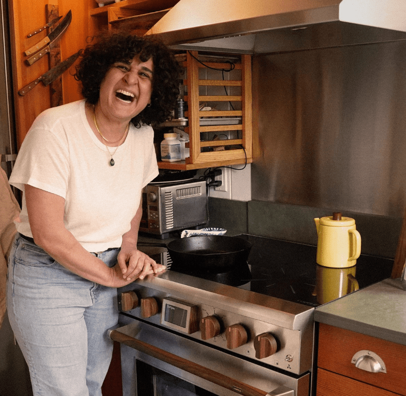 A woman leans over a plug-in, electric stove