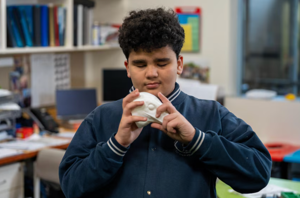 Blind student holding a model of a hawk's head