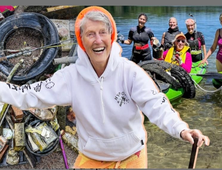 older woman in hoodie smiling with group of women behind her at a lake