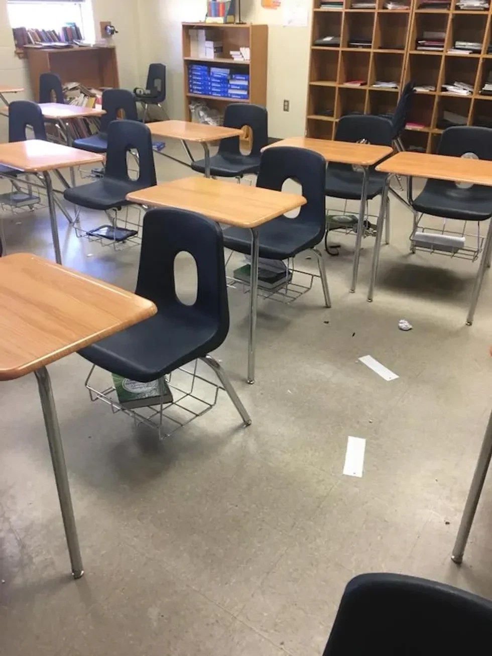 A dirty classroom with trash on the floor.