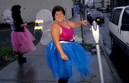 Two women dressed like fairies next to parking meters.