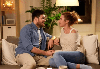 Man and woman on a couch holding hands