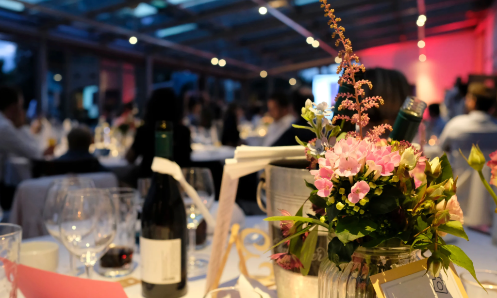 A dining table at a wedding reception with champagne bottles and flowers.