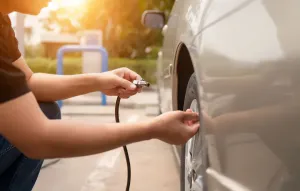 Man inflating car tires at a gas station.
