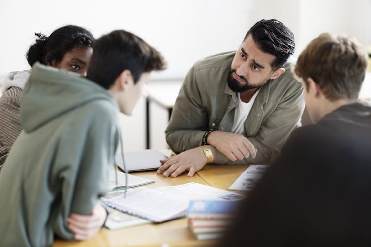 Thoughtful man seated at table with three teenagers